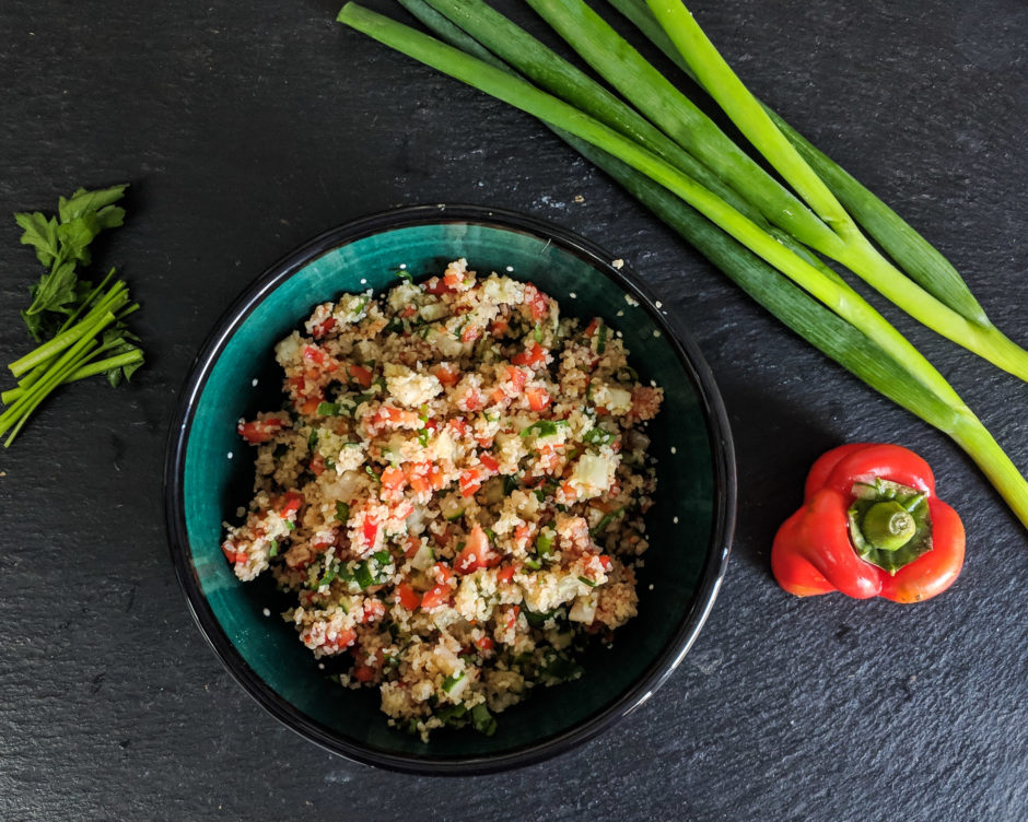 Salat mit Bulgur, umring von Lauchzwiebeln, Paprika und Petersilie