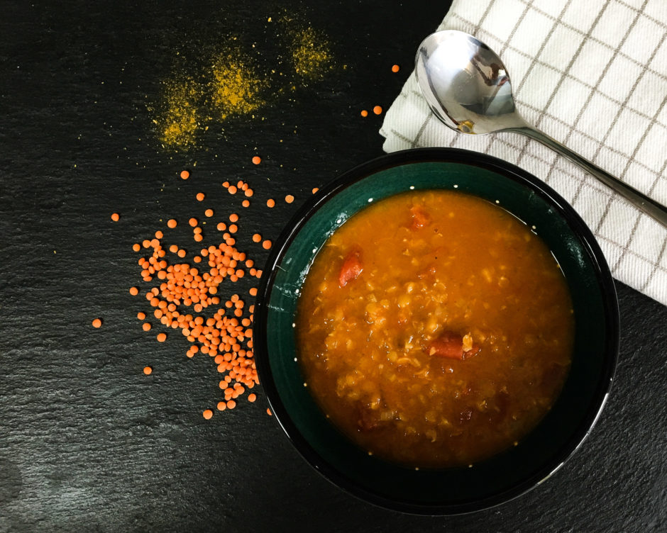 Suppenteller mit Linsen, Currypulver, Küchenhandtuch und Suppenlöffel